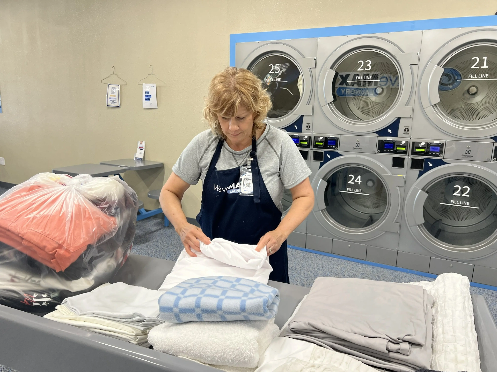 Theresa folding fresh wash & fold orders in front of our row of Electrolux dryers