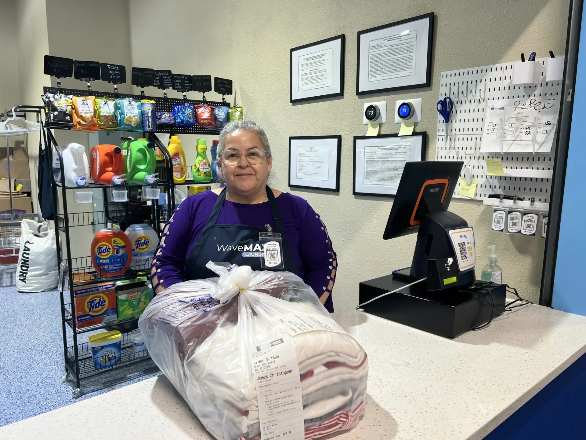 Grace at the WaveMAX front counter with a finished wash & fold order ready for pickup